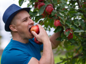 Man from Elkhart biting an apple with his sturdy new dental implants.